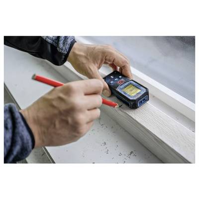 Eine Person verwendet ein digitales Lasermessgerät, um eine Holzoberfläche mit einem roten Bleistift zu markieren und präzise Messung und Markierung zu demonstrieren.