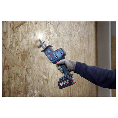 Eine Person mit Handschuhen verwendet eine kabellose Säbelsäge, um eine Holzplatte zu durchtrennen. Die Säge ist in einem präzisen Winkel ausgerichtet.