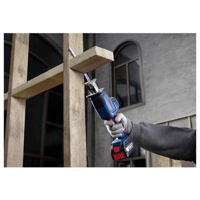 Eine Person trägt einen Handschuh und verwendet eine blau-schwarze Säbelsäge, um einen Holzbalken in Innenräumen zu durchtrennen.