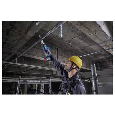 Ein Bauarbeiter mit einem gelben Schutzhelm verwendet ein Elektrowerkzeug, um Metallrohre an einer unfertig wirkenden Betondecke zu schneiden oder anzupassen.