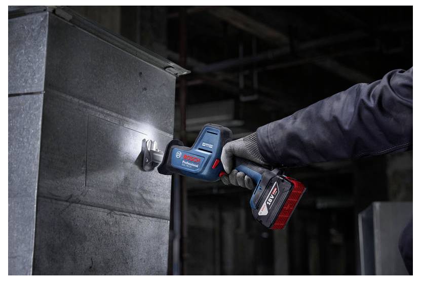 Eine Person nutzt ein Elektrowerkzeug, um Blech zu schneiden und dabei die Präzision und Kraft des Werkzeugs zu demonstrieren. Die Umgebung ist industriell und schwach beleuchtet.