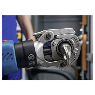 Nahaufnahme eines hydraulischen Crimpwerkzeugs, das eine Metallmuffe presst. Eine Person in blauer Kleidung steht im Hintergrund, unscharf.