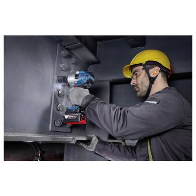 Ein Arbeiter, der einen kabellosen Schlagschrauber verwendet, um Bolzen an einer großen Metallstruktur zu befestigen, trägt einen Schutzhelm und Sicherheitsbrille zum Schutz.