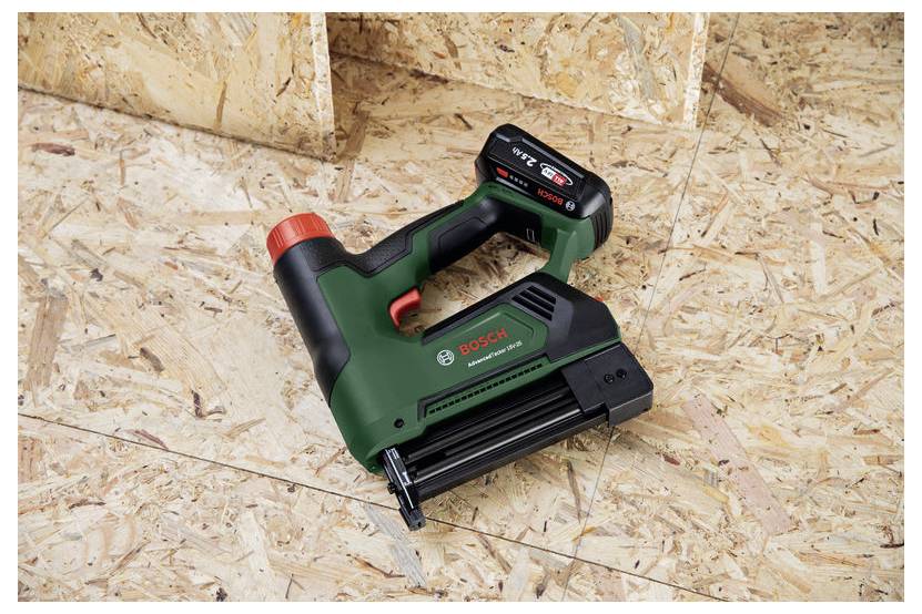 Eine Bosch Akku-Nagelmaschine auf einem Sperrholzboden, vor einer Holzvertäfelung.