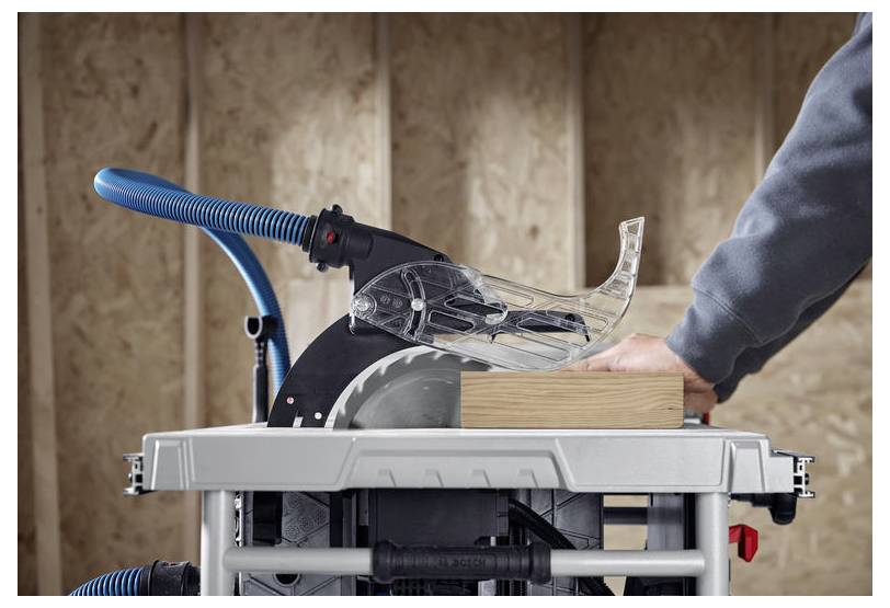 Eine Person verwendet eine Kreissäge mit Staubsaugeranbau, um in einer Werkstattumgebung eine Holzplanke zu sägen und dabei auf Sicherheitsmerkmale zu achten.