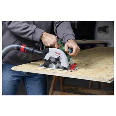 Eine Person verwendet eine Bosch-Kreissäge, um eine Holzplatte auf einer Werkbank zu schneiden. Der angeschlossene Saugschlauch sammelt Staub.