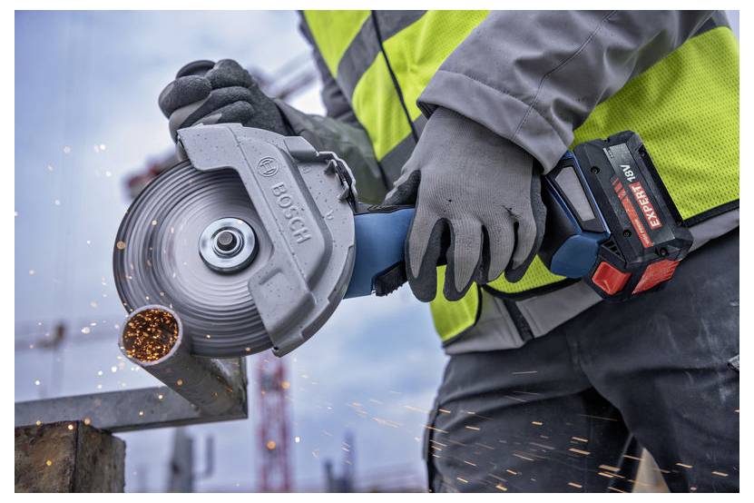 Eine Person, die einen elektrischen Winkelschleifer verwendet, um Metall zu schneiden, wobei Funken sprühen. Die Person trägt Sicherheitsausrüstung einschließlich Handschuhen und einer Warnweste.