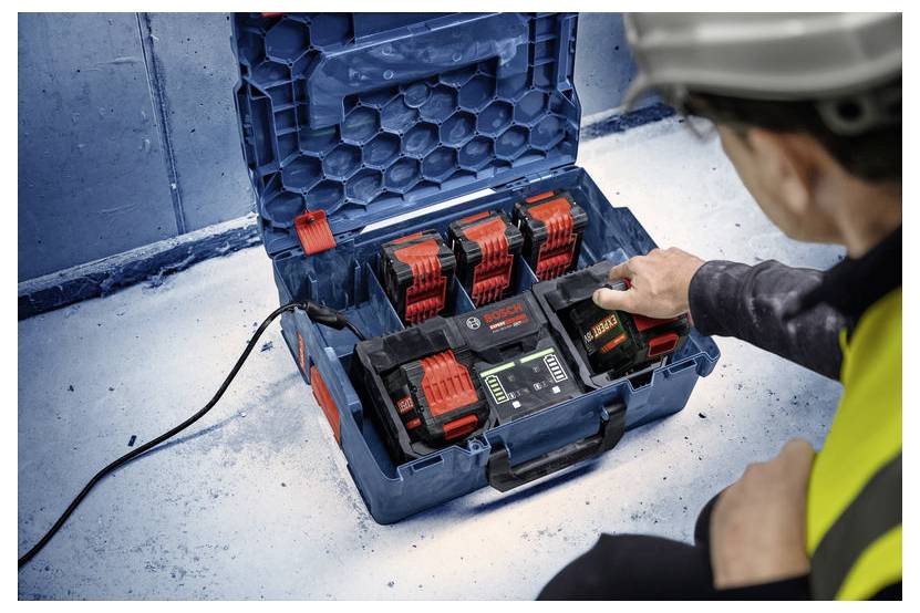 Eine Person mit Schutzausrüstung bedient eine Bosch-Batterieladestelle mit mehreren Batterien in einem blauen Transportkoffer.