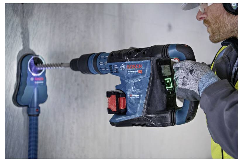 Eine Person, die einen Bosch Professional Bohrer an einer Betonwand verwendet, mit Sicherheitsausrüstung, und eine effiziente Bohrtechnik demonstriert.