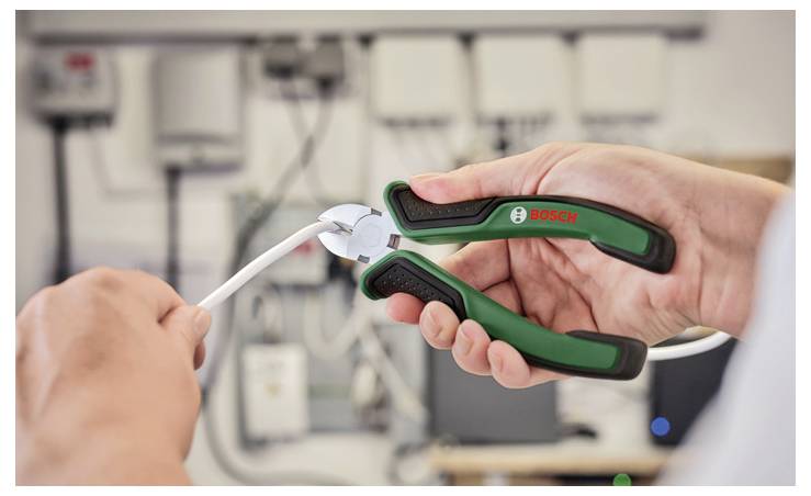 Eine Hand verwendet Bosch-Zangen, um einen weißen Draht in einer Werkstattumgebung zu durchtrennen.