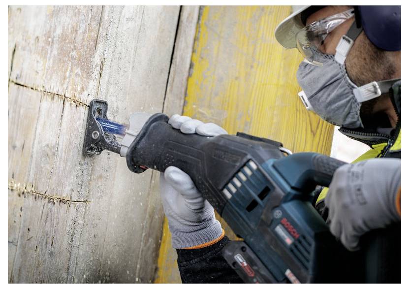 Arbeiter in Schutzausrüstung verwendet eine Kreissäge, um einen Holzbalken auf einer Baustelle zu schneiden.