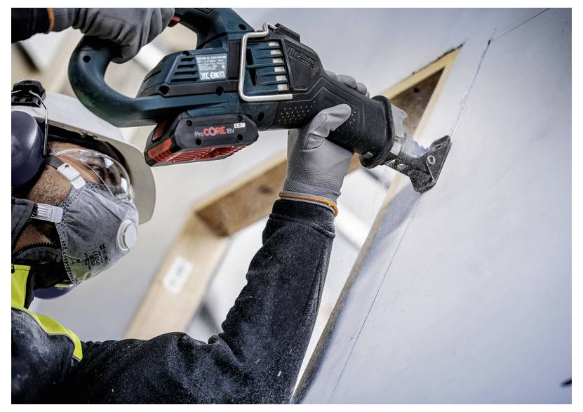 Eine Person mit Sicherheitsausrüstung bedient eine Kreissäge, um eine Gipskartonplatte zu durchtrennen, wobei der Fokus auf Präzision und Sicherheit in einem Baustellenumfeld liegt.