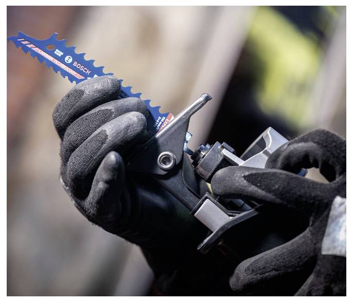 Eine Person mit schwarzen Handschuhen schiebt eine blaue Bosch-Sägeblatt in ein Elektrowerkzeug und konzentriert sich darauf, es sicher zu installieren.