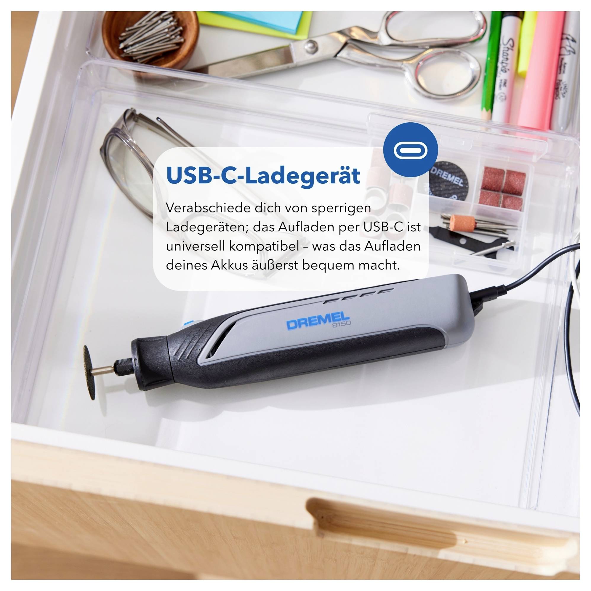 Eine Schublade mit Werkzeugen und Bastelbedarf, mit einem Dremel-Werkzeug neben einer Notiz, die die USB-C-Ladekompabilität betont.