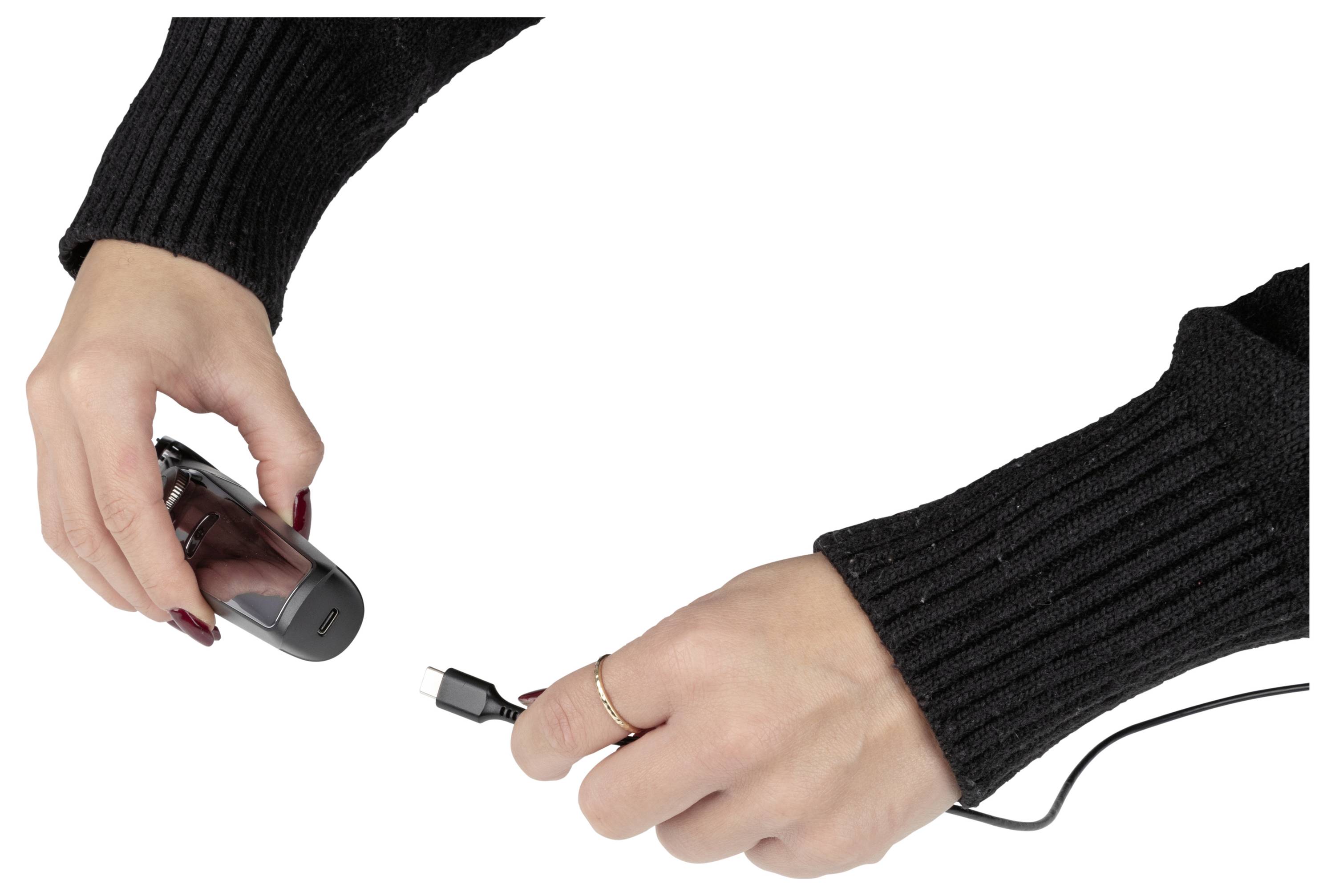 Eine Person, die ein kleines Gerät in ihrer linken Hand hält, während ihre rechte Hand ein Kabel in das Gerät einsteckt.