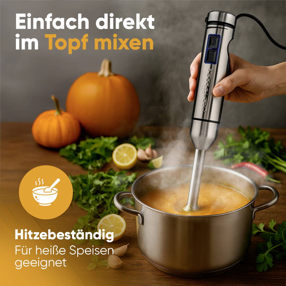 'Ein Handmixer wird direkt in einem dampfenden Topf mit Suppe verwendet. Im Hintergrund sind Kürbisse und Zitronen zu sehen.'