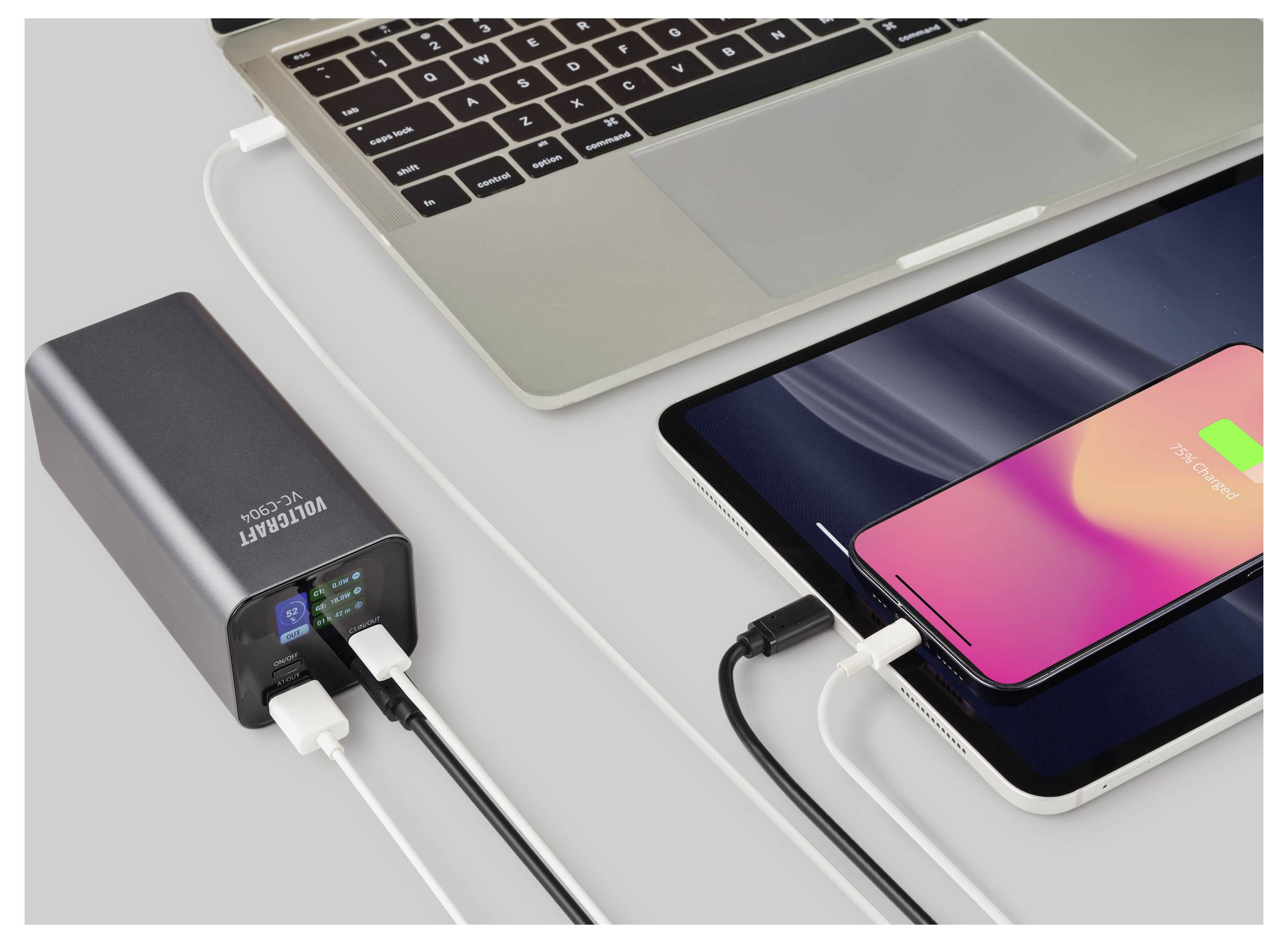 Ein Laptop, Tablet und Smartphone sind mit einer VELCANT Powerbank verbunden, wobei Kabel die gleichzeitige Aufladung anzeigen.