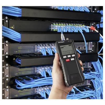 Eine Hand, die einen Netzwerk-Kabeltester vor einem Serverrack mit sorgsam angeordneten blauen Kabeln und Netzwerkswitches hält.