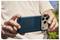 Eine Person hält ein Smartphone horizontal und richtet die Kamera aus, als würde sie draußen ein Foto machen. Das Handy befindet sich in einer blauen Hülle.