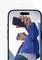 Eine Person mit blauer Jacke und Sonnenbrille macht mit einem Smartphone ein Selfie, während sie vor modernen Glasgebäuden unter einem klaren Himmel steht.