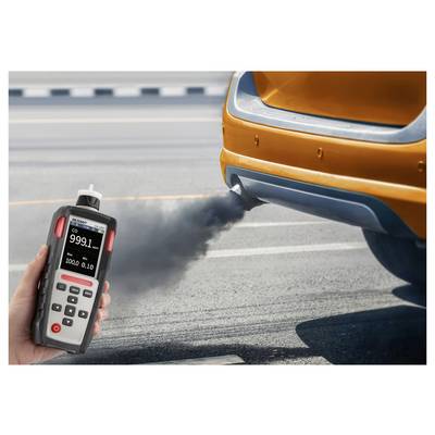 Ein Bild zeigt eine Hand, die ein Emissionsprüfgerät hält, das Autoabgase misst; das digitale Display zeigt "CO 999,1 ppm" an. Ein orangefarbenes Auto stößt schwarzen Rauch aus dem Auspuffrohr auf einer Straße aus.