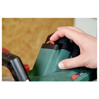 Eine Hand drückt den Einschaltknopf eines grün-schwarzen elektrischen Werkzeugs, was dessen Betrieb signalisiert.