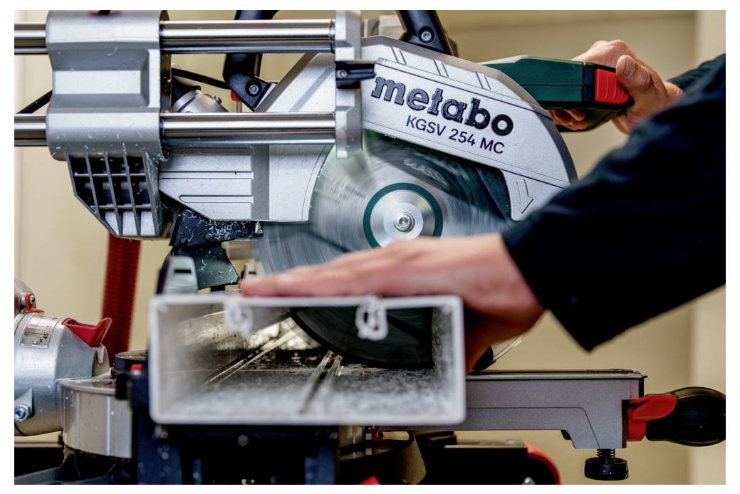 Eine Person verwendet eine Kreissäge, um präzise durch ein Metallrohr zu schneiden. Die Säge ist mit 'metabo KGS 254 MC' beschriftet.