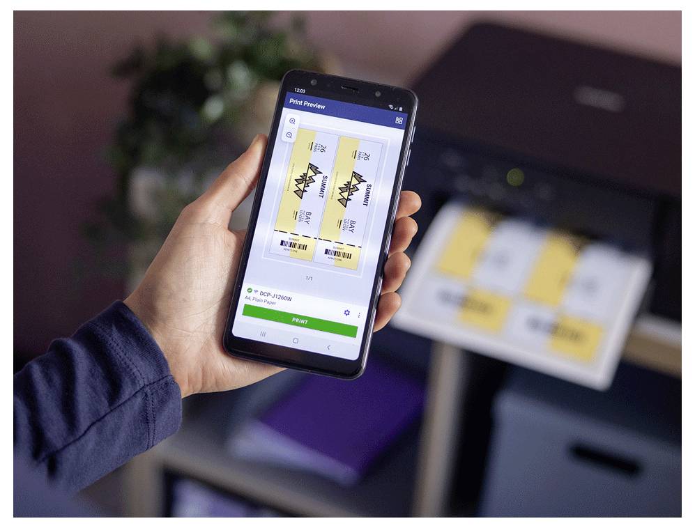 Eine Person hält ein Smartphone mit PDF-Tickets, die zum Ausdrucken bereit sind. Ein nahegelegener Drucker druckt gerade ähnliche Tickets aus.