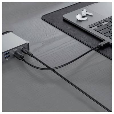 Ein Laptop auf einem Schreibtisch ist über Kabel mit einem USB-Hub mit mehreren Anschlüssen verbunden, daneben liegen kabellose Ohrhörer.