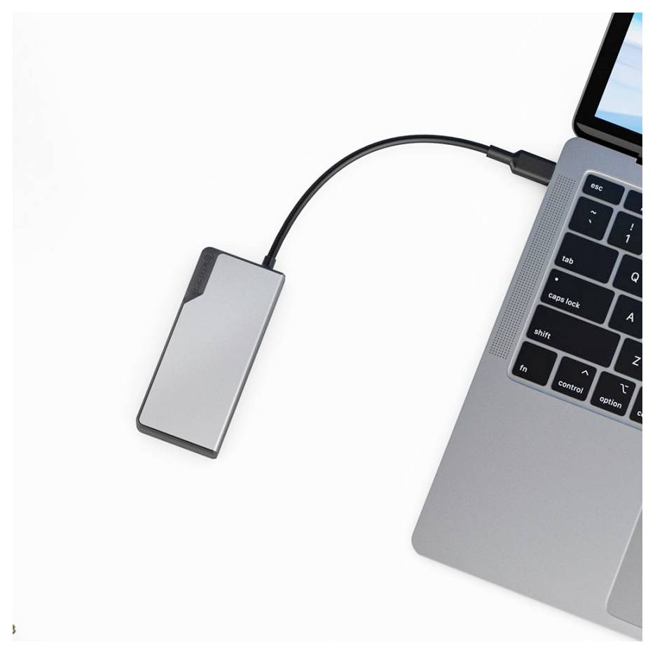 Eine silberne externe Festplatte ist über ein kurzes Kabel mit einem Laptop verbunden und befindet sich auf einer weißen Oberfläche.