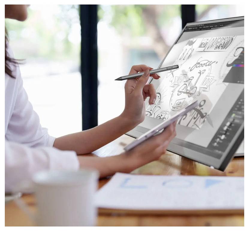 Eine Person verwendet einen digitalen Stift auf einem Touchscreen-Computer und skizziert Designs. Ein unscharzes Notizbuch und eine Tasse sind im Vordergrund sichtbar.
