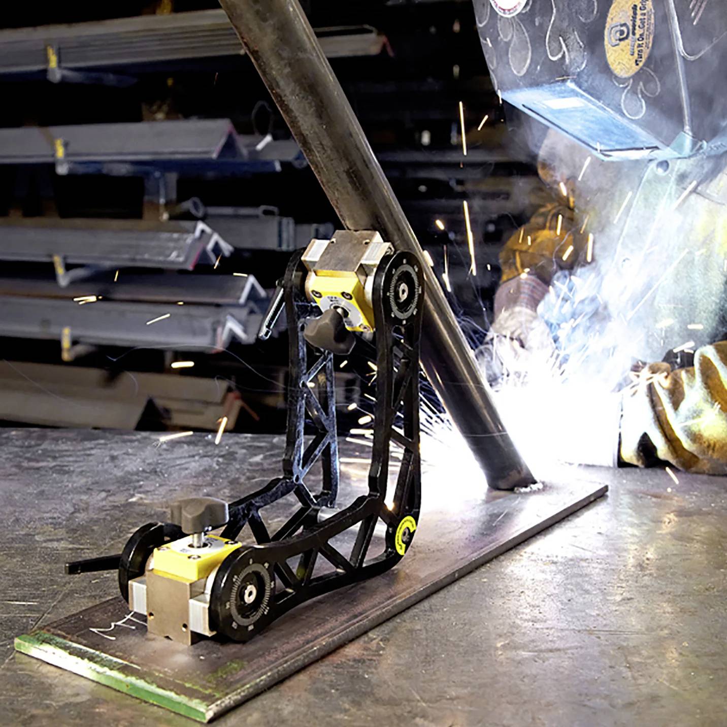 Ein robotischer Schweißarm in Aktion, Funken sprühend, beim Fabrizieren einer Metallstruktur in einer industriellen Werkstattsumgebung.