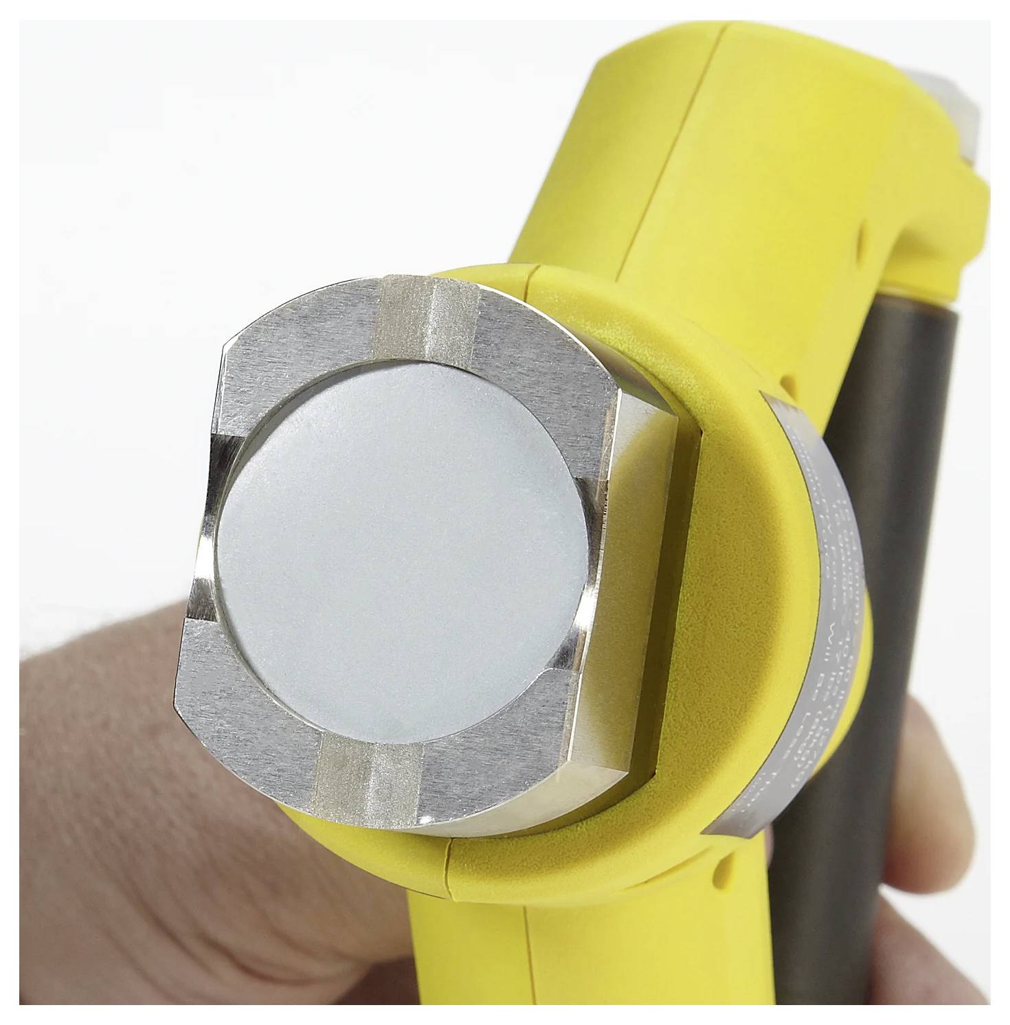 Ein Nahaufnahme einer Hand, die ein kompaktes, gelbes tragbares Werkzeug mit einer kreisförmigen metallischen Komponente am Ende hält, höchstwahrscheinlich ein Sensor oder ein Magnet.