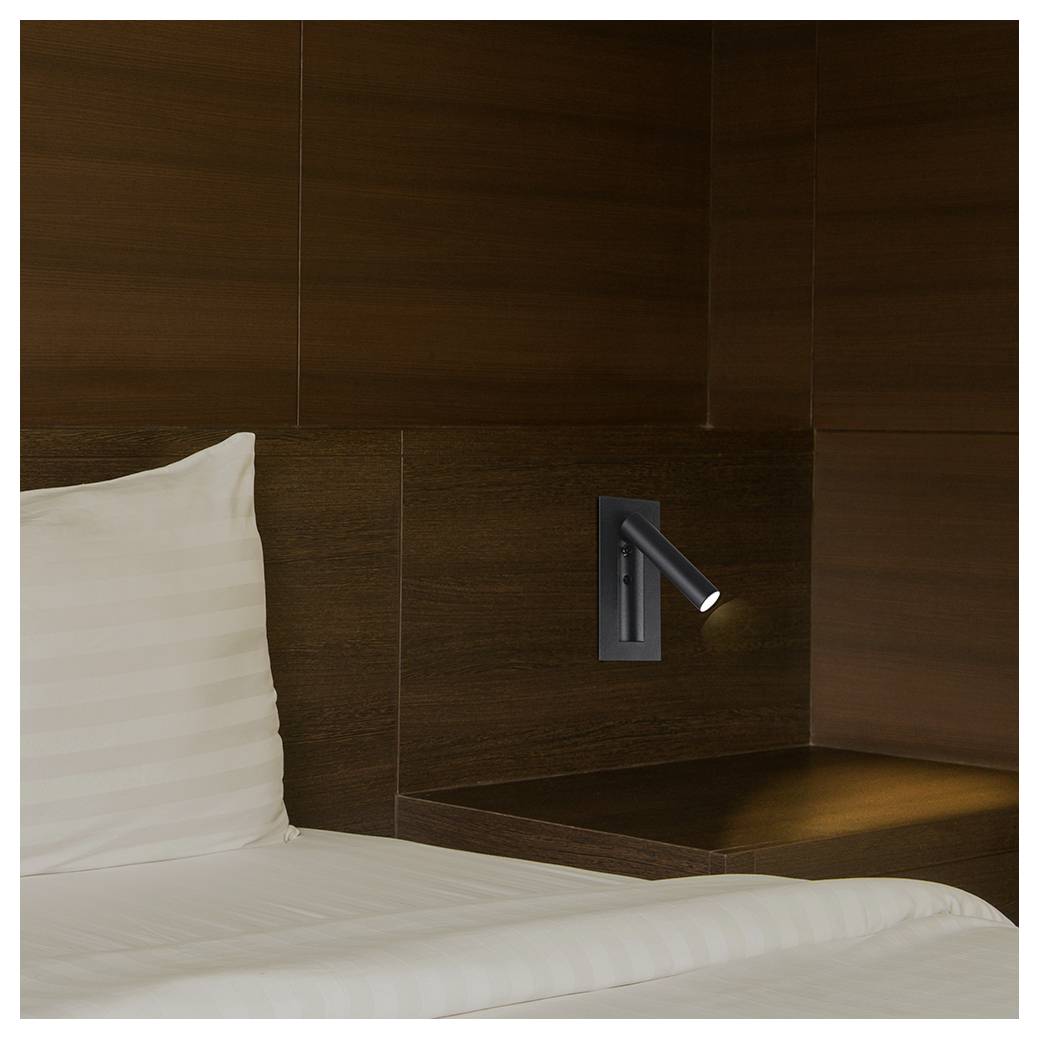 Ein modernes, minimalistisches Hotelzimmer mit dunkler Holzvertäfelung und einem weiß gestreiften Bettlaken. Eine elegante, wandmontierte Leselampe ist eingeschaltet.