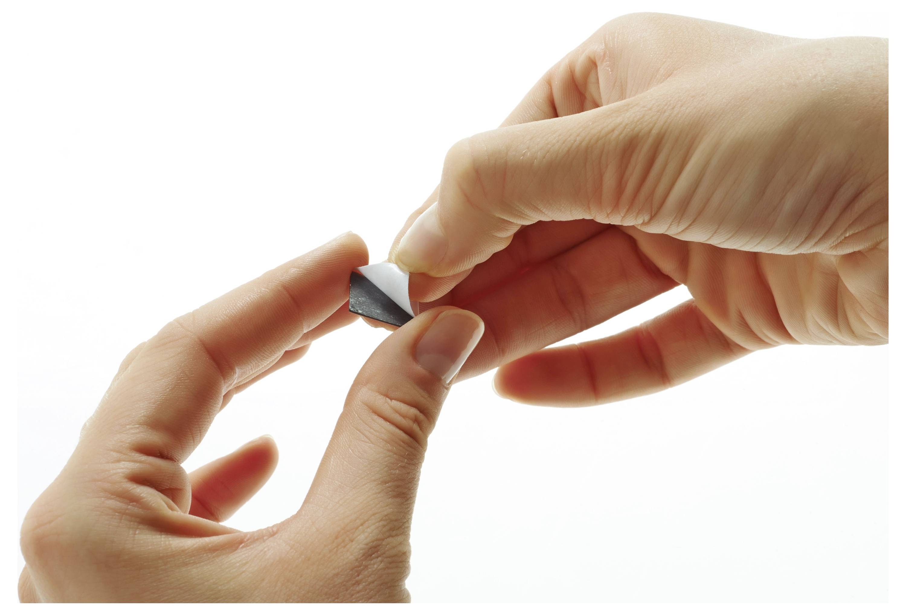 Hände, die einen kleinen schwarzen dreieckigen Aufkleber vor einem weißen Hintergrund abziehen.