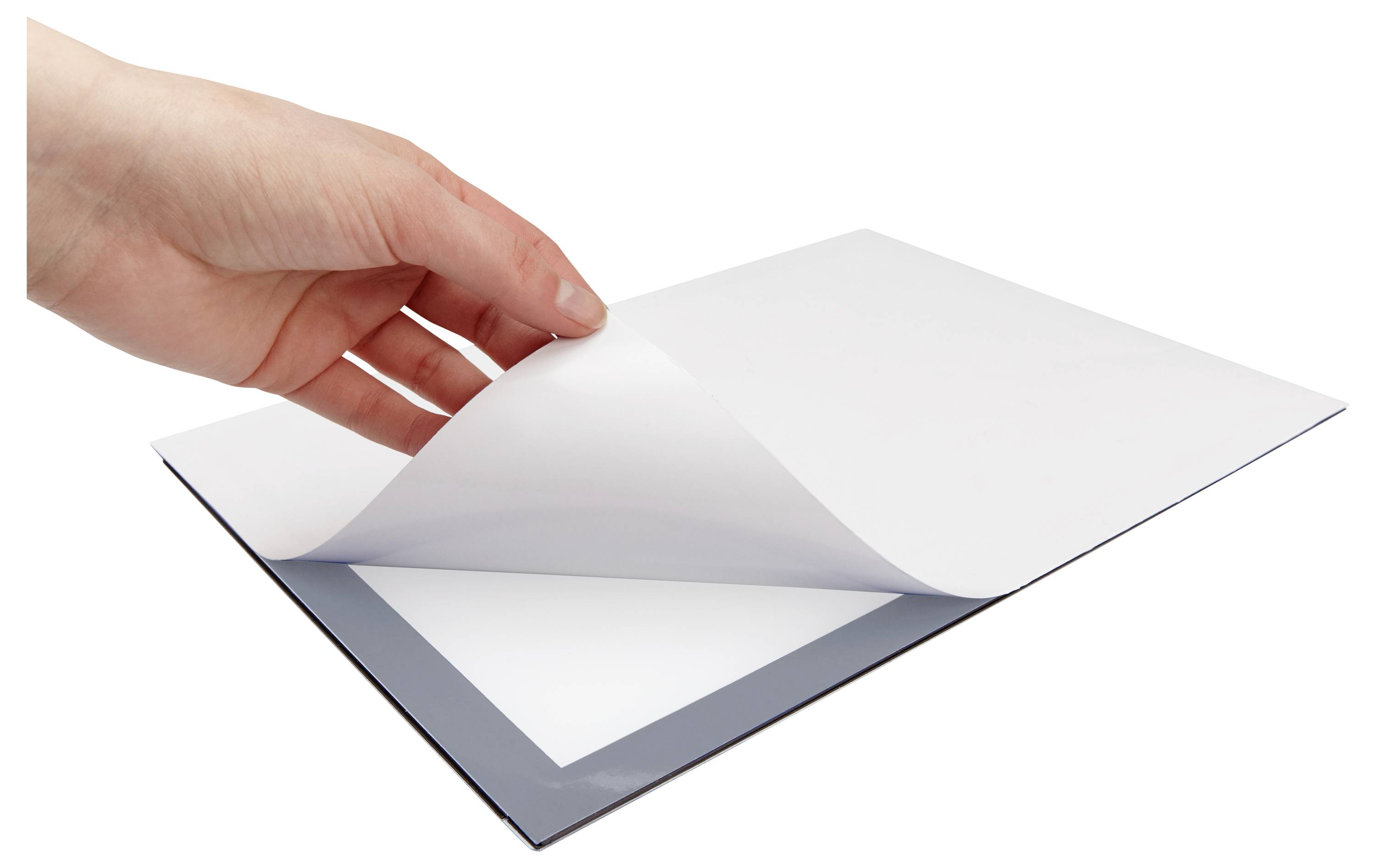 Eine Hand, die ein Blatt glänzendes, transparentes Folie von einem Stapel auf einem Tisch hebt und dabei eine leuchtend weiße Oberfläche darunter freilegt.