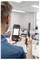 Eine Person hält ein Luftqualitätsmessgerät und ein mobiles Gerät, auf dessen Bildschirm Luftqualitätsdaten angezeigt werden, in einem modernen Büroraum.
