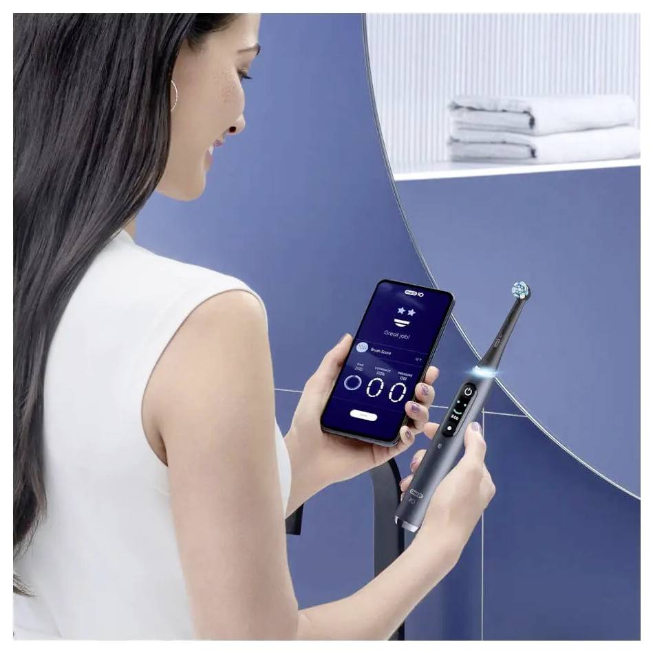 Eine Frau bedient eine App auf ihrem Smartphone zur Steuerung einer hochmodernen elektrischen Zahnbürste und zeigt damit die Integration von Technologie in der Zahnpflege.