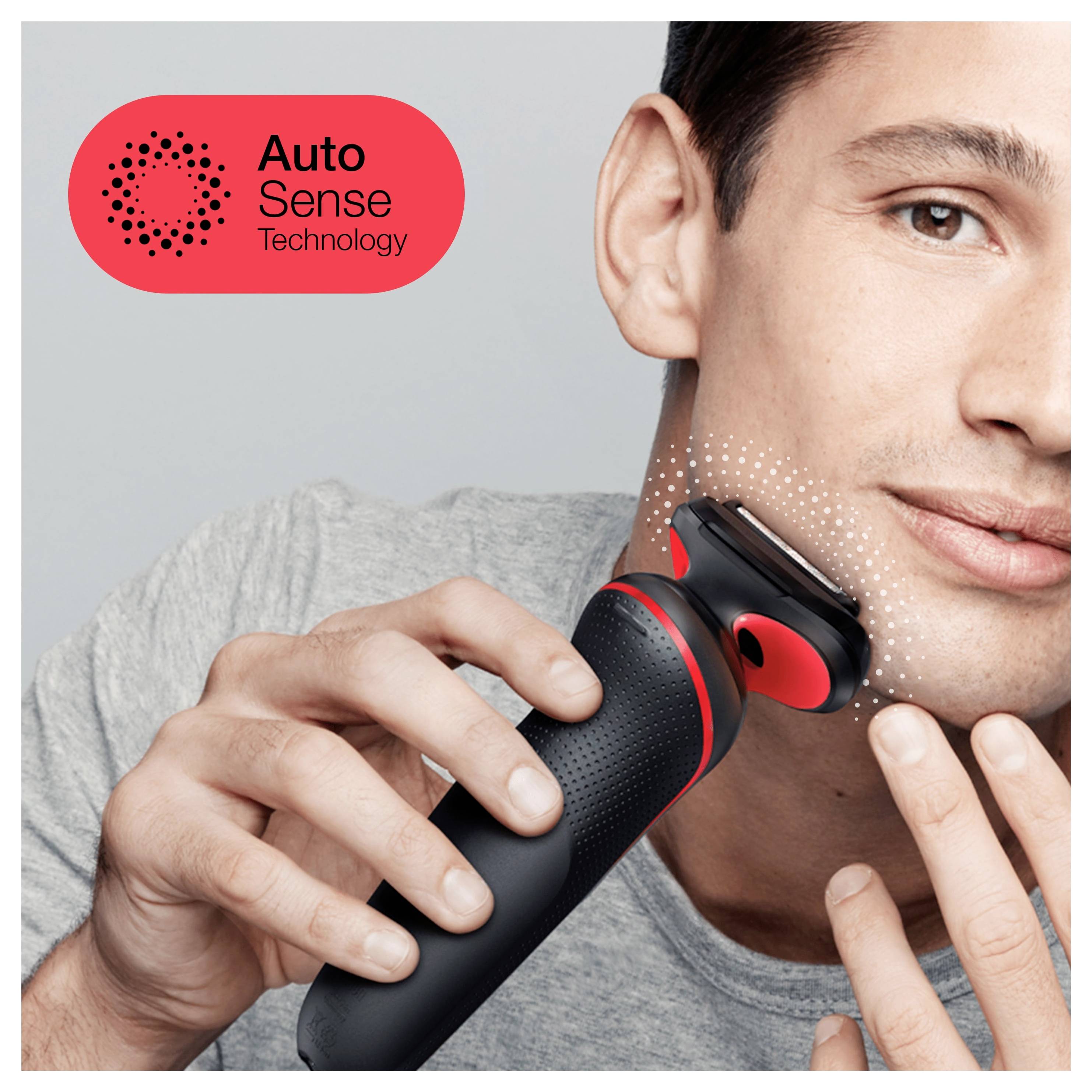 Ein Mann benutzt einen schwarzen und roten elektrischen Rasierer mit der Aufschrift "Auto Sense Technologie". Die nahe Positionierung des Rasierers an seinem Gesicht unterstreicht seine Verwendung zur Körperpflege.