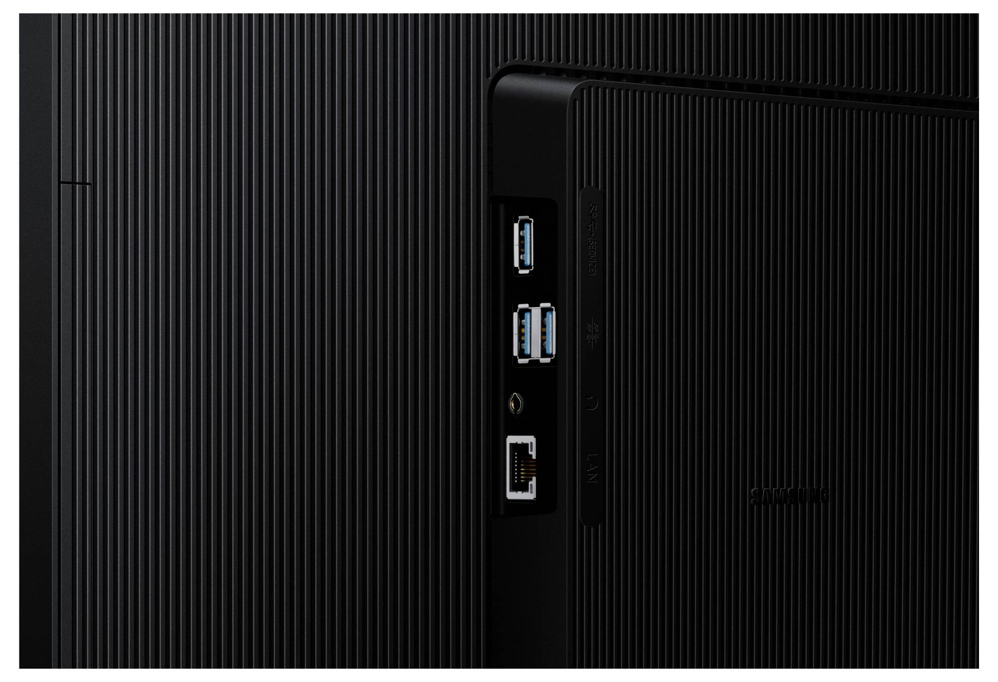 Schwarzes elektronisches Gerät mit drei USB-Anschlüssen, einem Ethernet-Anschluss und einem kreisförmigen Audioport auf einer strukturierten Oberfläche.