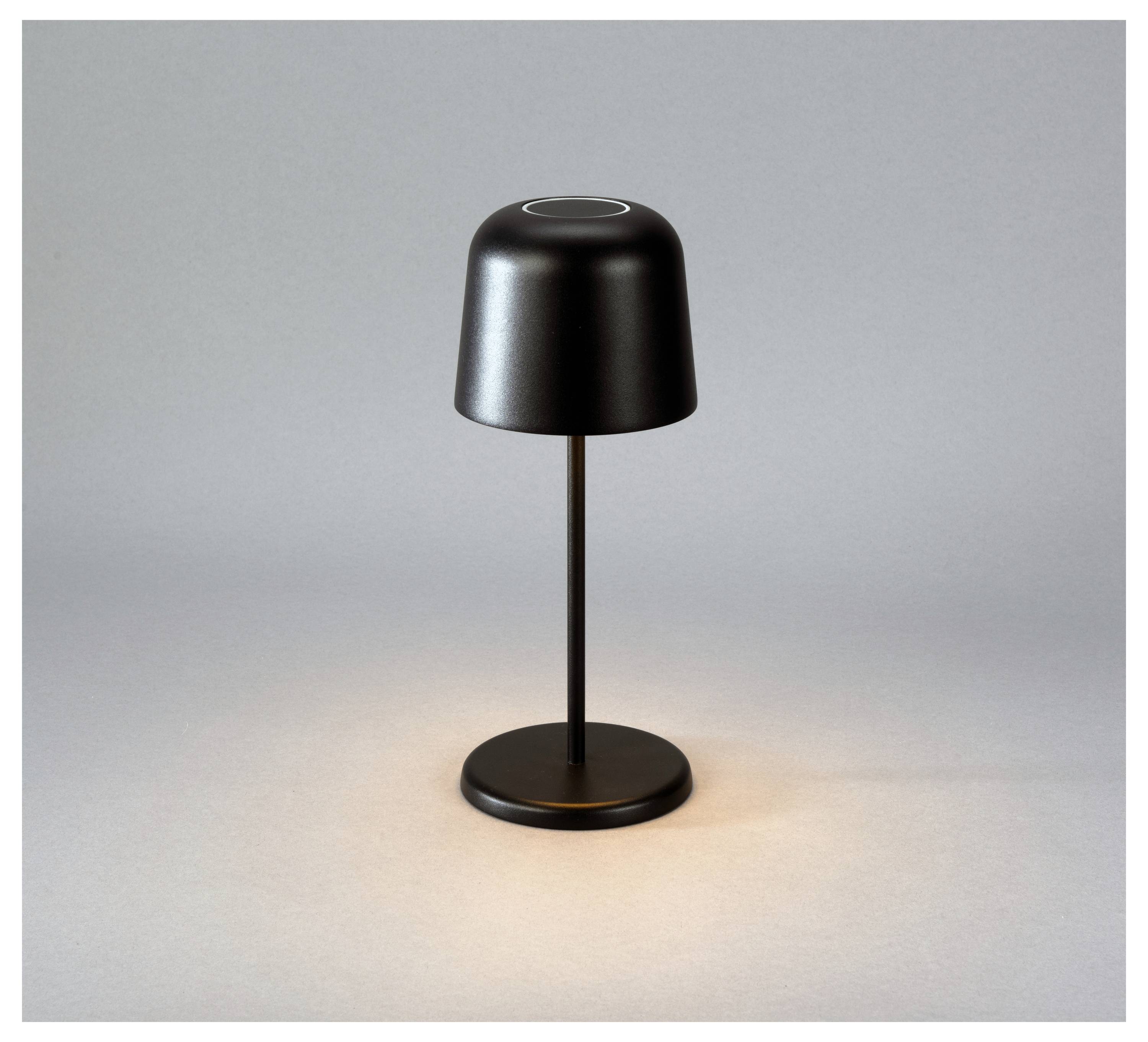 Eine moderne Tischlampe in mattem Schwarz mit einem zylindrischen Lampenschirm, die ein weiches, warmes Licht auf einer grauen Oberfläche verbreitet.