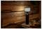 Ein gemütlicher Holzraum zeigt eine einzigartige Lampe, die aus einer Glasflasche mit einem gestreiften Lampenschirm auf einem runden Tisch besteht, neben Kaffeetassen und Weizen.