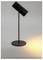 Eine moderne schwarze Schreibtischlampe, die ein warmes kreisförmiges Licht auf eine graue Oberfläche wirft und ein minimalistisches Design mit einem zylindrischen Kopf und einem schlanken Ständer präsentiert.