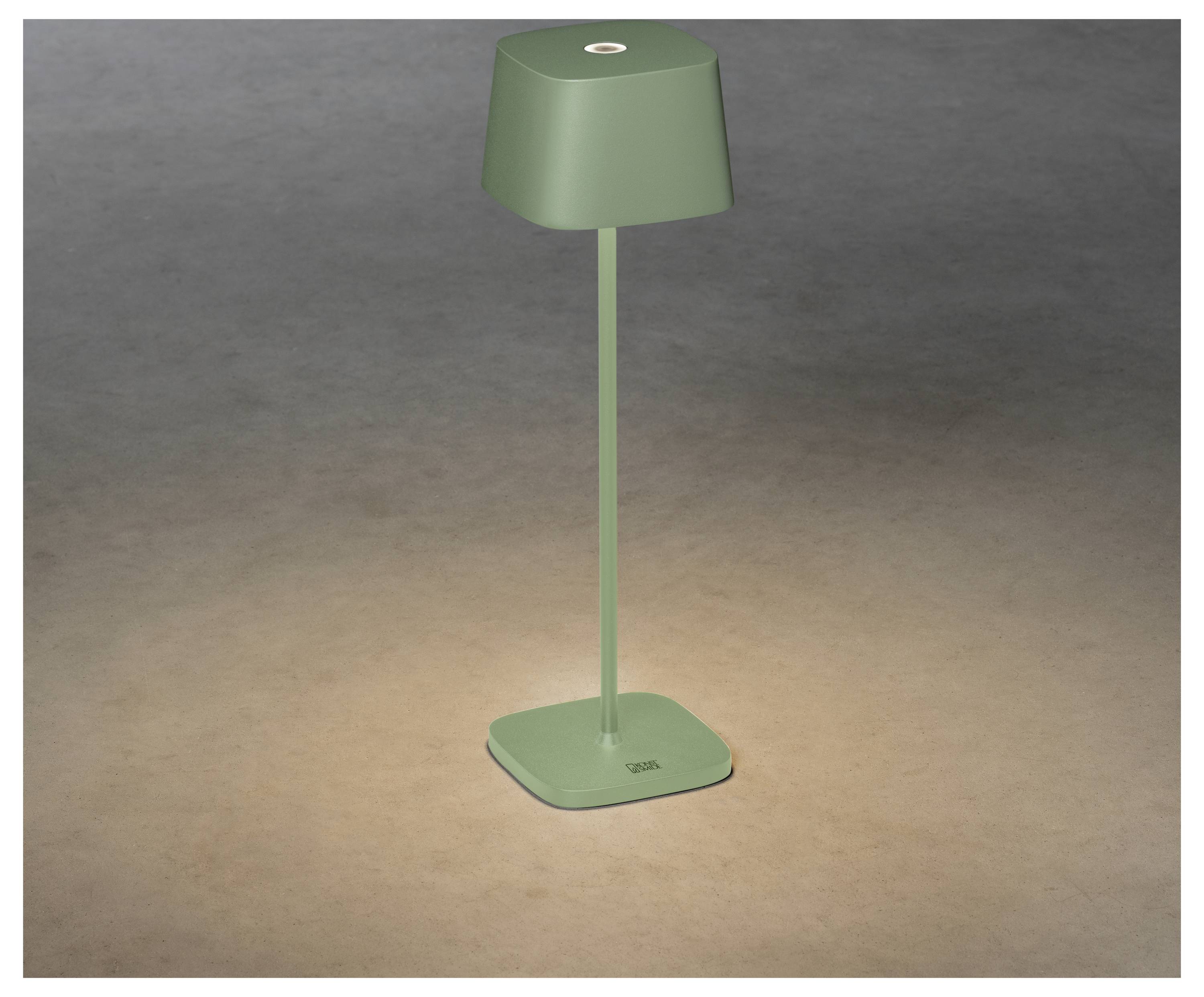 Eine schlanke, moderne grüne Tischlampe mit quadratischem Fuß und Schirm, die ein warmes, gezieltes Licht auf eine strukturierte Oberfläche wirft.