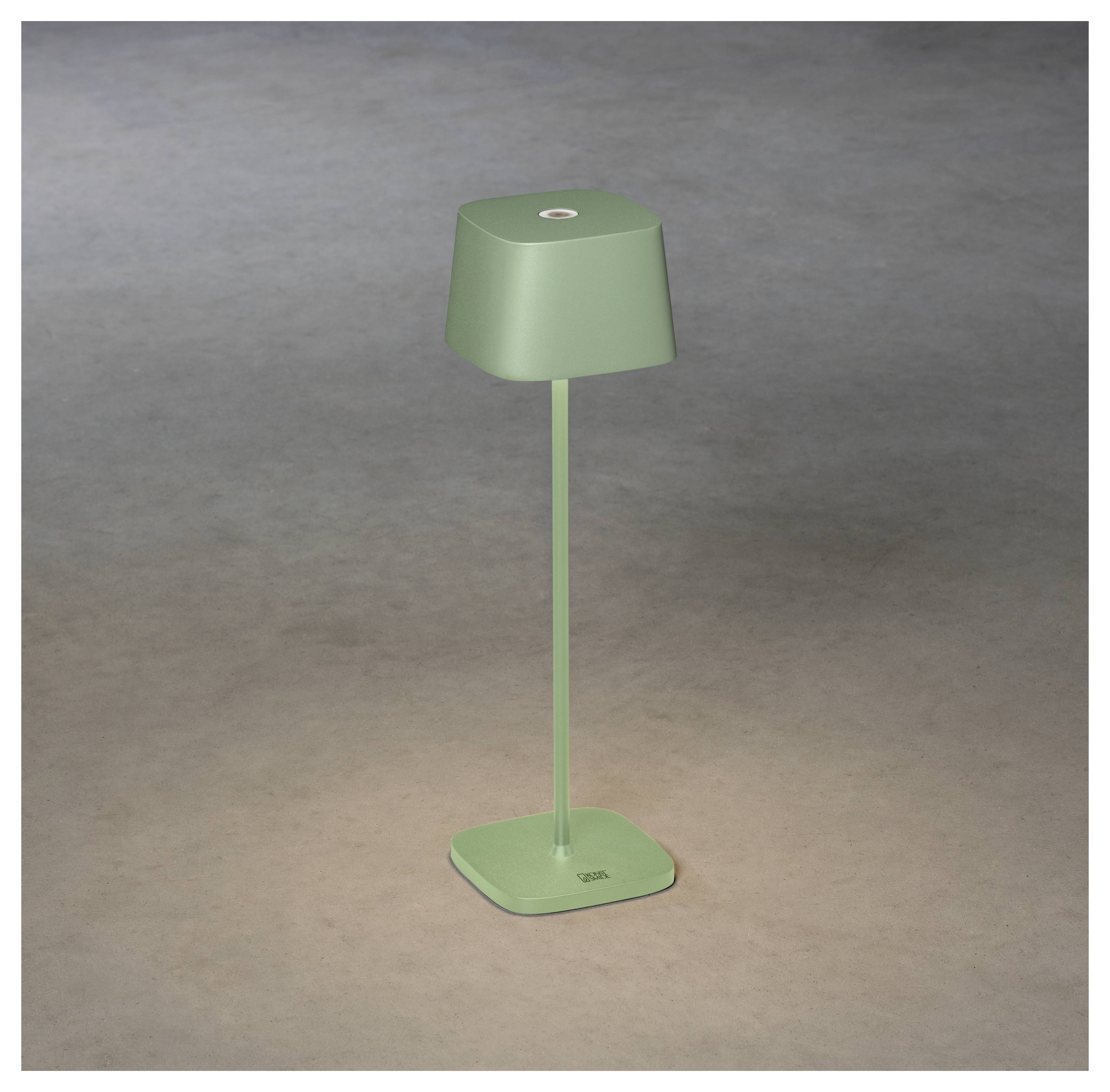 Eine moderne, minimalistische grüne Tischlampe mit quadratischer Basis und eckigem Lampenschirm steht auf einer schlichten Oberfläche.