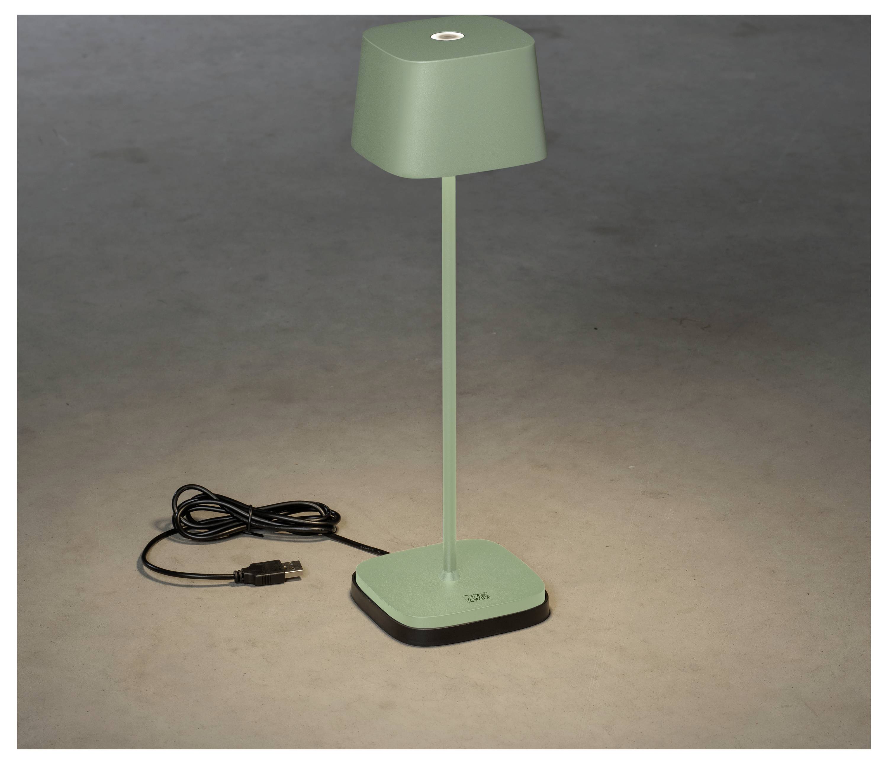 Eine grüne, moderne Schreibtischlampe mit quadratischem Fuß und Lampenschirm, eingesteckt und wirft ein kleines Licht auf eine graue Oberfläche.