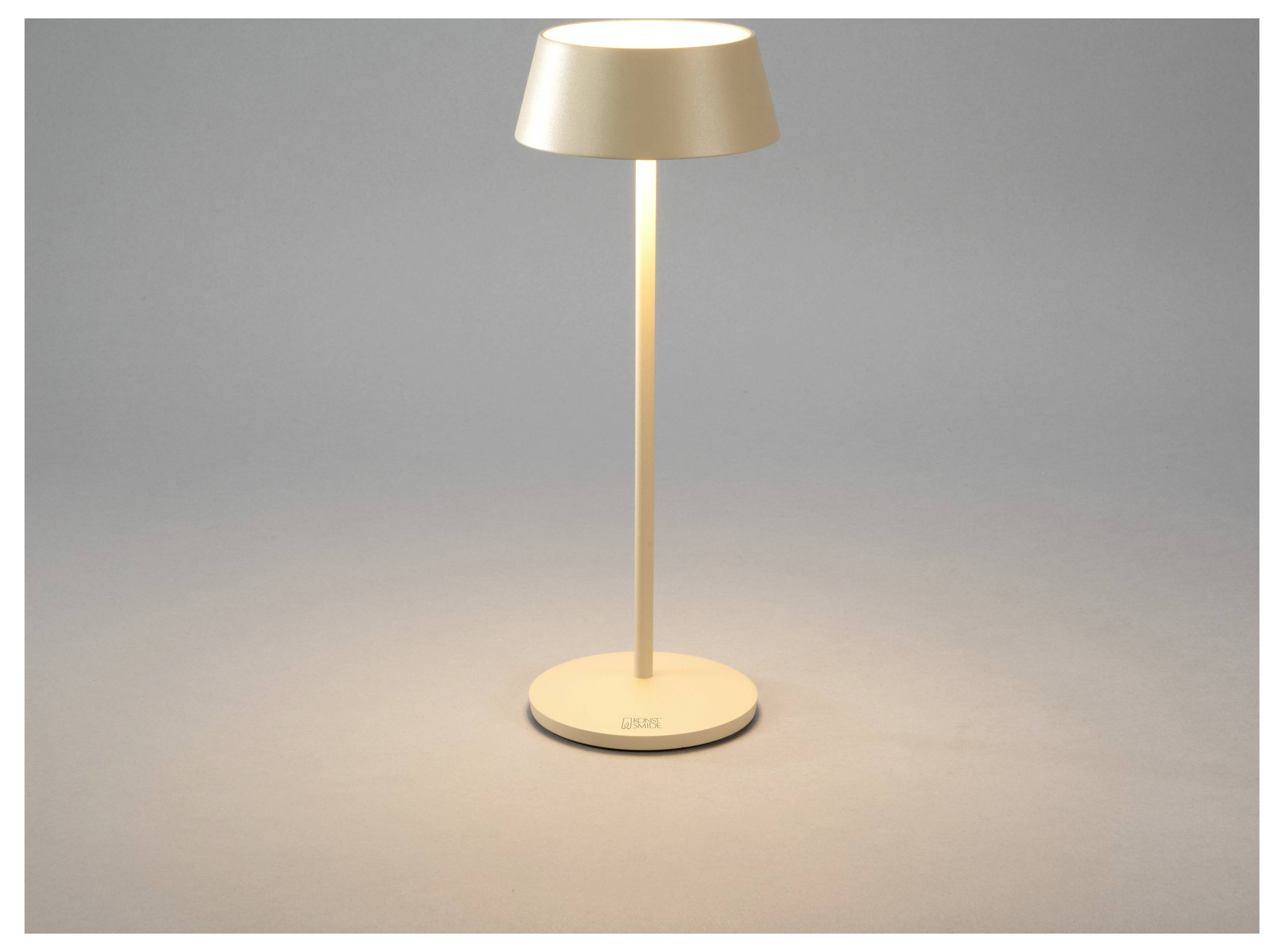 Eine moderne, minimalistische Tischlampe mit runder Basis und zylindrischem Lampenschirm, die warmes Licht auf eine neutrale Oberfläche wirft.
