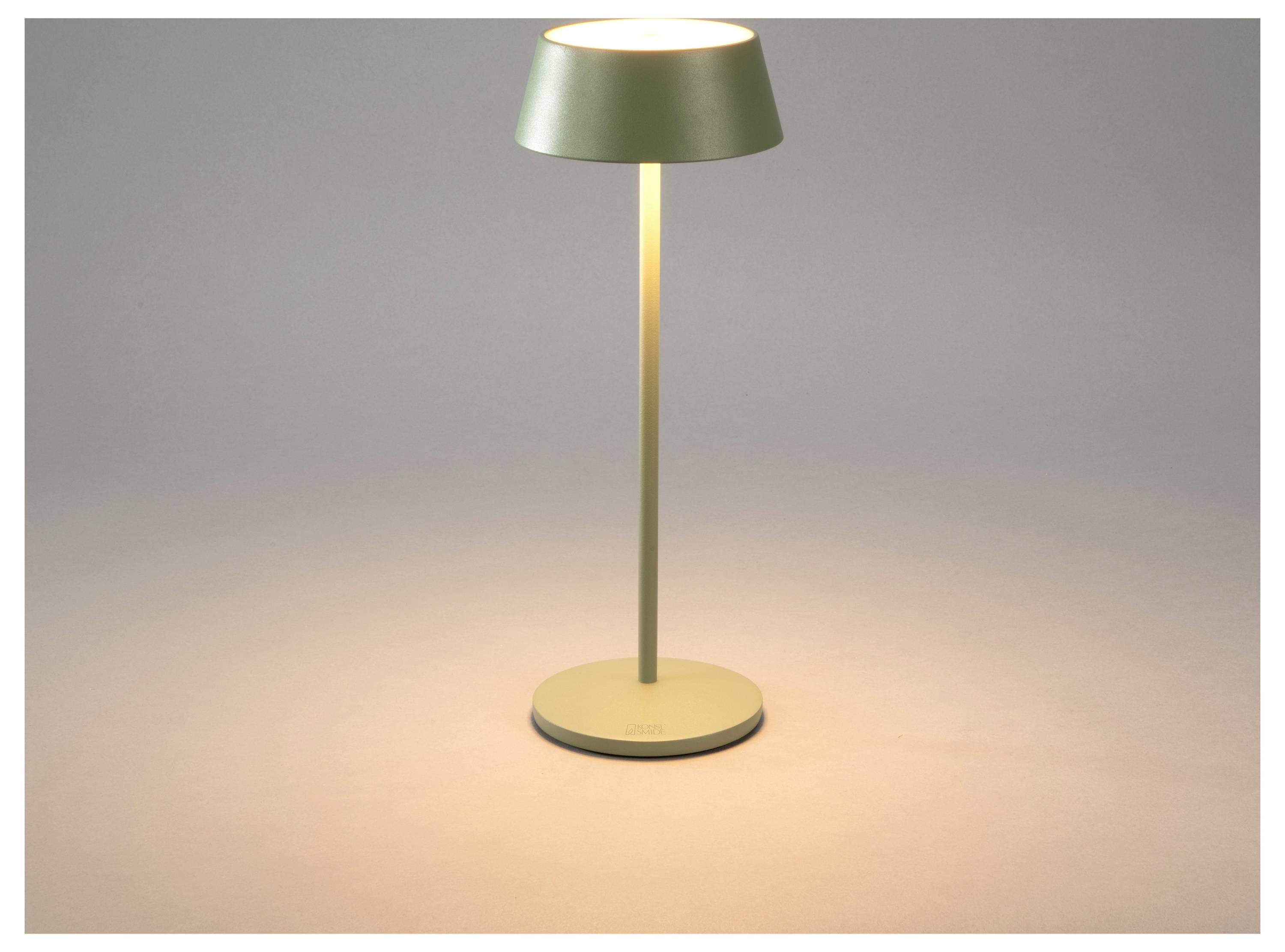 Eine schlichte, minimalistische Tischlampe mit einer zylindrischen Basis und einem runden Lampenschirm, die in einer dämmrigen Umgebung ein warmes, weiches Licht ausstrahlt.