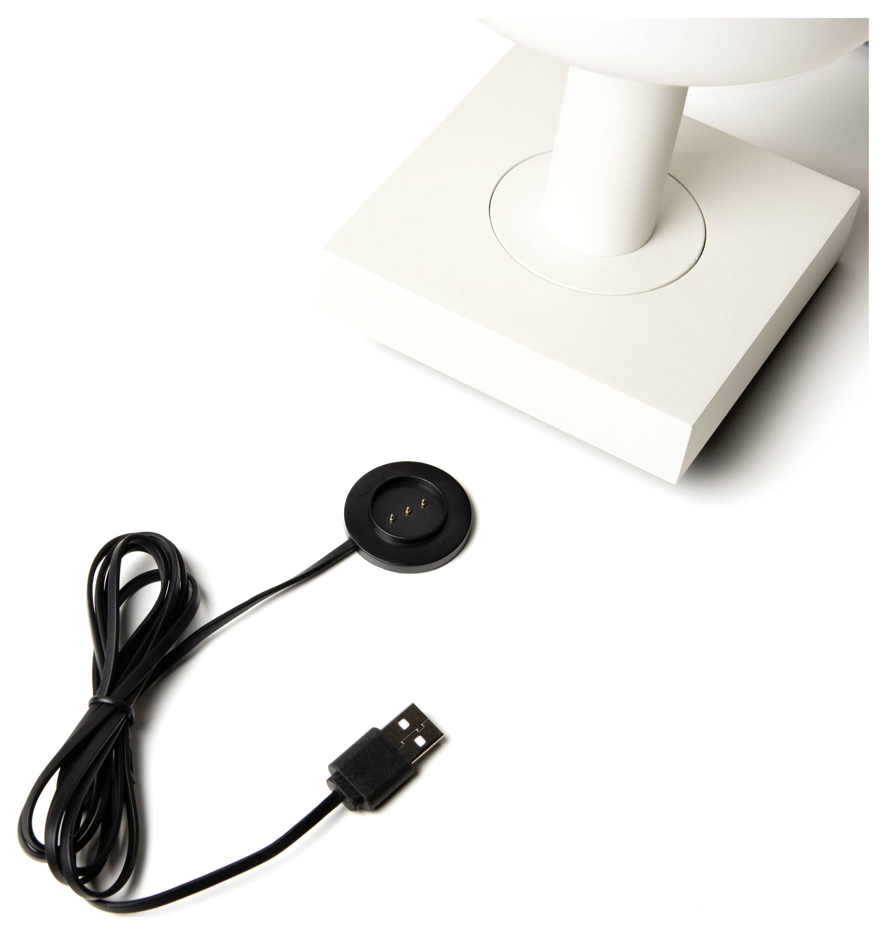 Ein schwarzes USB-Ladekabel mit einem kreisförmigen magnetischen Anschluss wird neben der Basis einer weißen Lampe gezeigt.