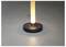 Eine moderne zylindrische Lampe verbreitet ein weiches, warmes Leuchten und steht auf einer glatten, grauen Oberfläche.